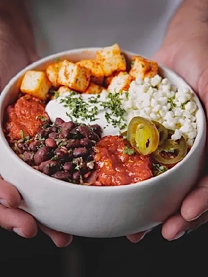 Here's my signature Mexican Burrito Bowl, held with care. It's a vibrant mix of seasoned rice, beans, paneer, and fresh salsa, all in one satisfying meal.