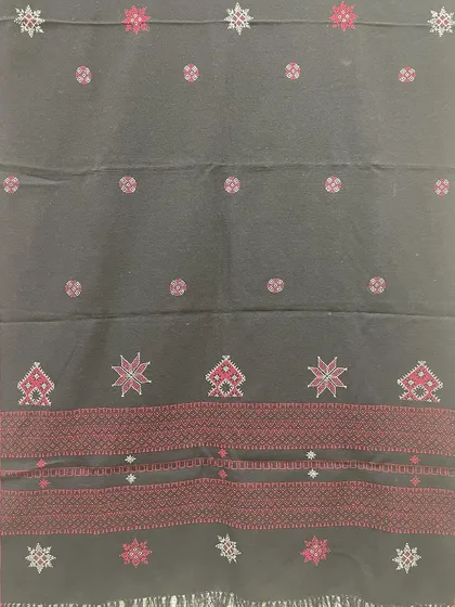 This black woollen shawl features a striking red border and motifs from Kasuti and Negi embroidery traditions. It's a bold and beautiful piece to keep you warm.