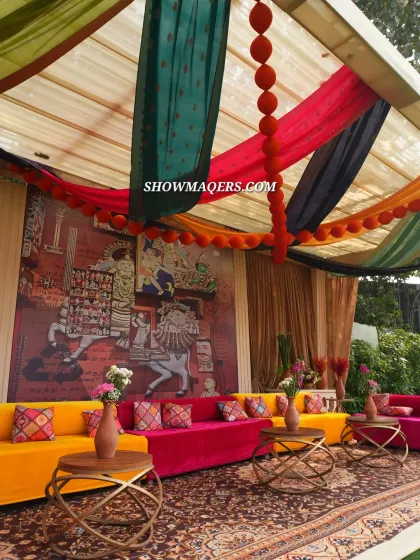 A vibrant lounge area from our 'Banarasia' themed Mehendi. We used colorful seating in fuschia and yellow, a traditional Persian rug, and a backdrop of Banaras art to create a lively and cultural atmosphere.