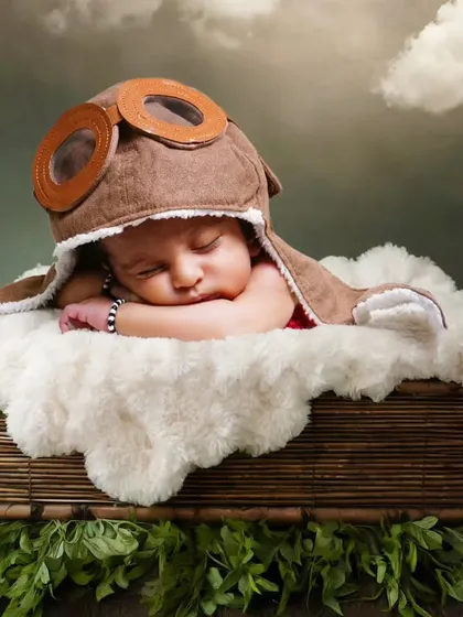 An adventurous aviator theme, with the baby wearing a pilot's cap and sleeping in a basket surrounded by clouds.