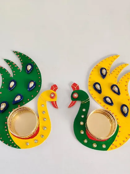 A pair of completed peacock T-light holders, showcasing the vibrant green and yellow color scheme.