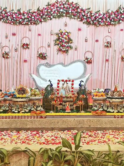 A beautiful engagement setup with a pink and white floral theme, featuring personalized caricature props and a full display of offering plates.