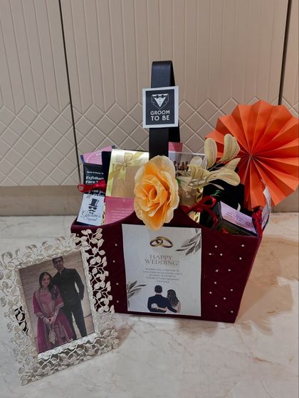A special hamper curated for the groom-to-be. This gift basket is styled with a handsome maroon and orange theme and includes a personalized photo frame to celebrate the happy couple.