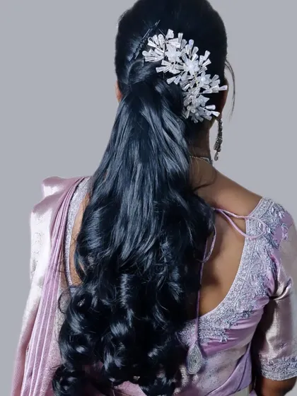 A modern and sleek half-up ponytail with soft waves. The look is elevated with a striking white crystal accessory, making it a great choice for a contemporary party look.