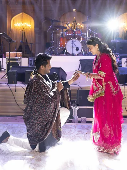 A romantic proposal moment on the Sangeet stage, with the groom on one knee. We help plan these surprise moments to ensure they are captured perfectly.