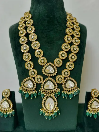 A long, layered necklace set with triangular Kundan pendants and green bead drops. This is a statement rental piece for a bride looking for something unique.