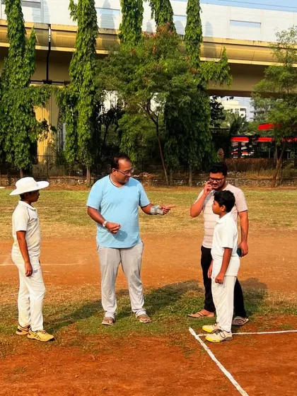 Coaching is a conversation. Here, I am discussing technique and strategy with two of my young players and a parent on the field. I believe in being personally involved, giving direct feedback to fix flaws and build a player's cricketing intelligence.