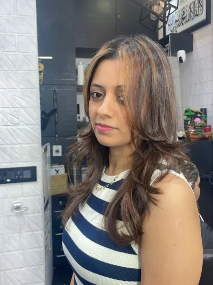 A chic, layered haircut with face-framing highlights, styled straight with a bit of texture.