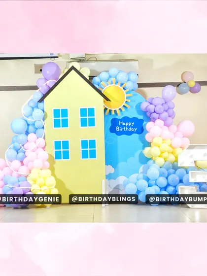 A clean and bright Peppa Pig backdrop, featuring the iconic yellow house, a sunny sky, and a pastel balloon garland.