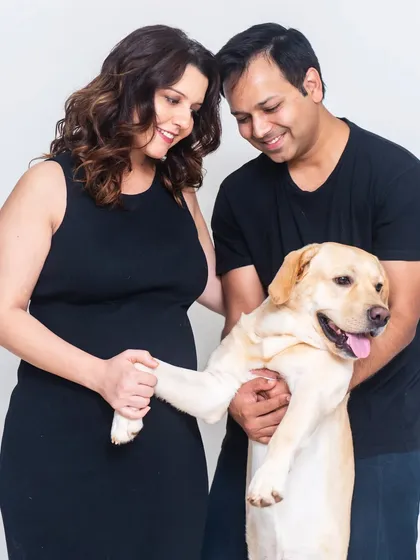 The whole family is getting ready for the new arrival. This studio portrait includes their beloved dog, who is giving a "high-five" to the baby bump.