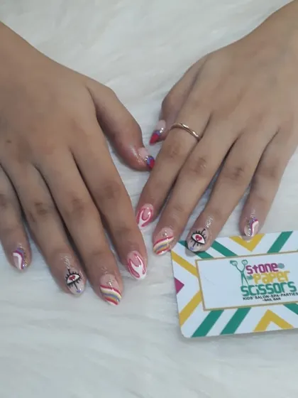 Another take on the evil eye trend, this time combined with bold red and white stripes on short, natural nails. It's a vibrant and eye-catching design.