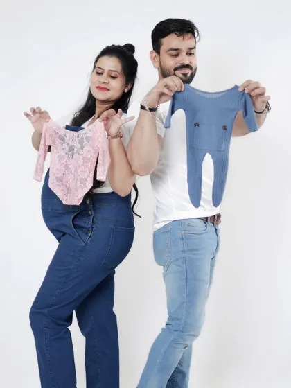 He or she, what will it be? This couple holds up both a pink and a blue outfit for a fun photo before the big reveal.