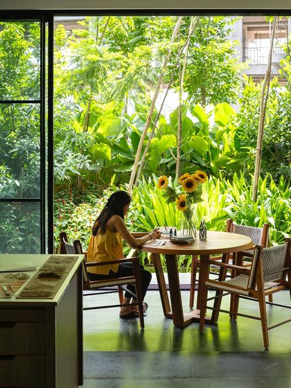A quiet moment of creativity by a large window overlooking a lush garden. The design prioritizes natural light and green views, creating an inspiring environment for both work and relaxation within the home.