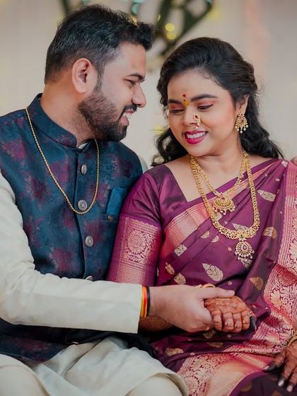 A quiet moment on the couch during their engagement celebration. The groom holds the bride's hand, sharing a look of love and affection.