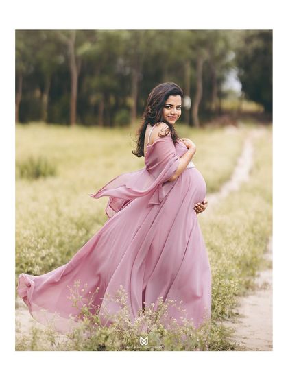 The mother-to-be looking back with a gentle smile. The movement in the flowy gown and her hair creates a dynamic and ethereal portrait.