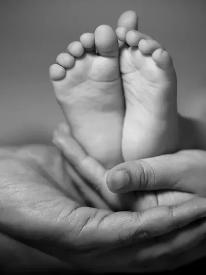 Sometimes, the smallest details hold the biggest love. This timeless black and white newborn photoshoot captures the tiny perfection of a baby's feet held safely in their parent's hands.