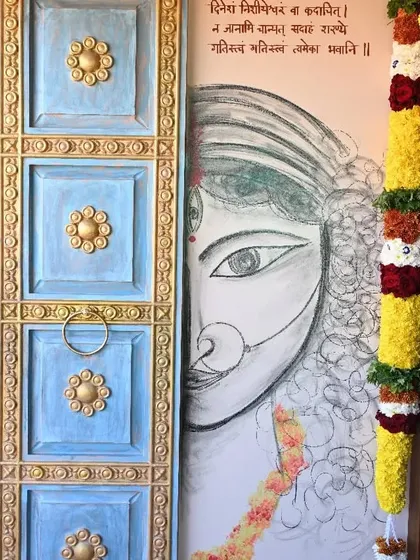 A simple yet powerful sketch of a goddess's face at the entrance of a home. Paired with a traditional door and a Sanskrit shloka, it creates a spiritually welcoming entryway.