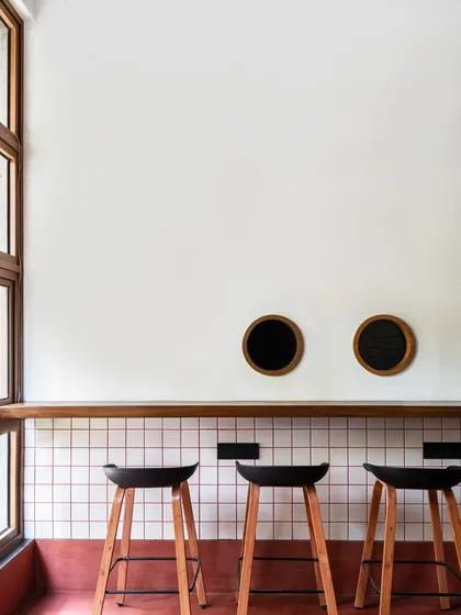 The bar seating at 'FLIP N FOLD' features simple, modern stools against a backdrop of white grid tiles with red grouting. This detail is part of a fresh, modern take on the retro American diner aesthetic, designed to complement the food it serves.
