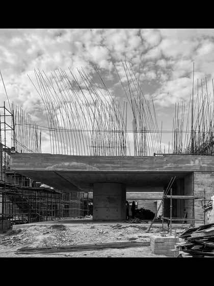A photograph taken during the construction of a villa in Moradabad. This image captures the raw power of the cantilevered concrete form and the forest of rebar, illustrating the brutalist honesty of the structure before it is fully enclosed.
