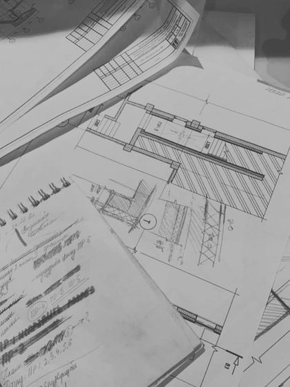 A glimpse into the countless hours of drafting and refinement. Architectural plans and hand-drawn details are layered on the drafting table, each line representing a decision made.