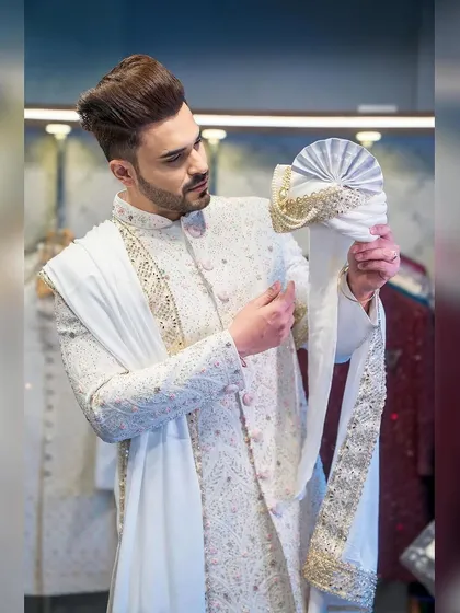 A groom's attire should be nothing short of magnificent. Here, influencer Ayush Khatri is seen during a fitting for his custom sherwani, a masterpiece of intricate embroidery and regal design, complete with a matching turban and stole.