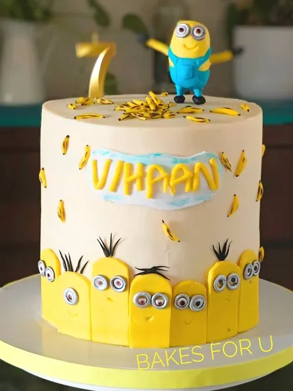 A fun Minions-themed cake surrounded by a crowd of little fondant minions. A larger minion figure stands on top, making it a perfect cake for fans of the yellow characters.