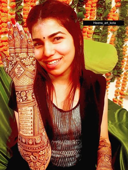 A happy bride showing off her personalized mehndi, which includes a special message written on her forearm.