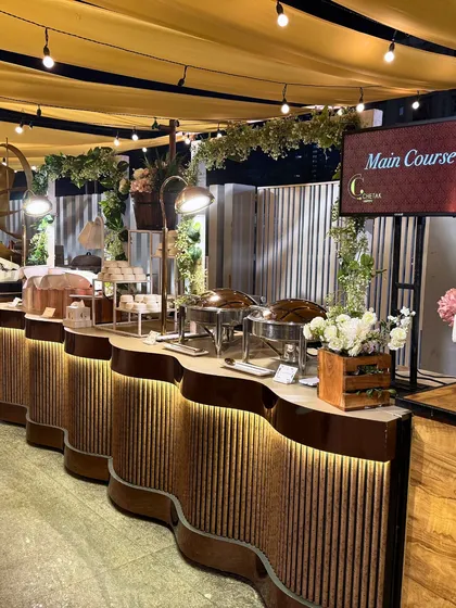 A main course station elegantly presented under a canopy of draped fabric and string lights. The setup includes professional chafing dishes and clear signage, ensuring a smooth and enjoyable dining experience.