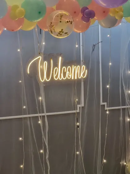 Detail shot of the "Welcome" neon sign against the sheer curtain with fairy lights.