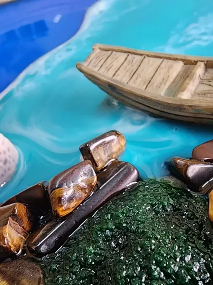 A close-up of the tiger eye stones and miniature boat in a seascape piece.