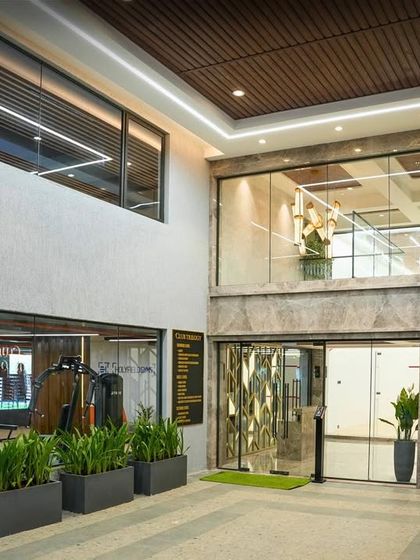 The entrance to the Club Trilogy at Ekta Tripolis. The double-height space and extensive use of indoor plants create a fresh and welcoming atmosphere, setting the stage for the vibrant recreational facilities inside.