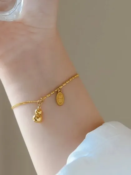 This delicate bracelet features a gourd and coin charm, symbols of good fortune. It's a unique and meaningful piece for everyday wear.