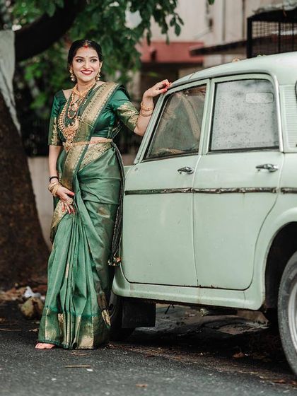 The vintage car adds a touch of classic charm to this maternity shoot. The deep green Kanchipuram silk saree is a timeless choice.