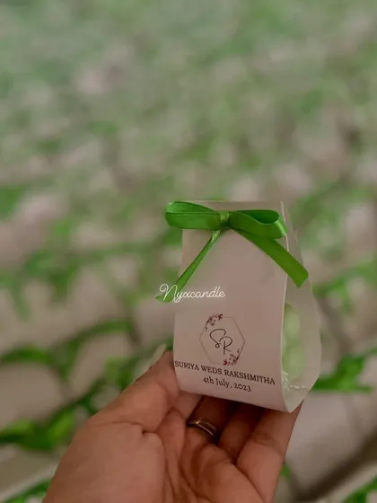 A close-up of the personalized packaging for a wedding order. These mini bubble candles come in a custom-designed box that features the couple's names and wedding date.