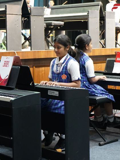 Two students practice side-by-side in their school's music lab. Our setup encourages both individual focus and peer learning, creating a supportive and collaborative environment for musical growth.