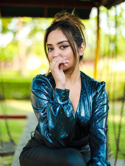 A close-up, pensive portrait of the model in the blue bodysuit, highlighting her makeup and the top's unique texture.