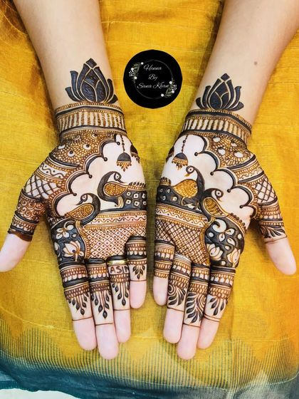 A vibrant and beautiful design with two peacocks facing each other, surrounded by jhumka (earring) motifs and topped with a lotus.