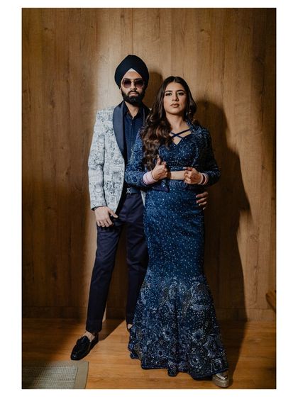 A full-length portrait of the stylish couple against a modern wooden backdrop. Their coordinated outfits and confident poses make for a great shot.