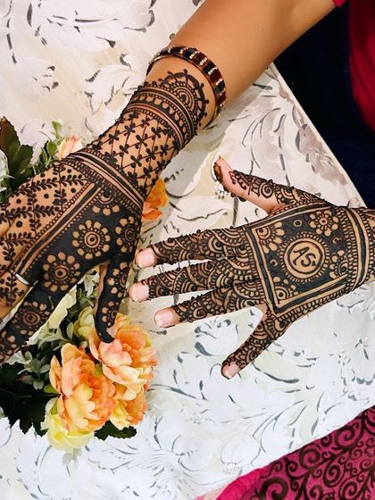 A beautiful pair of hands with contrasting but complementary designs. One features a star-flower jaal, while the other has a square initial box, both framed by intricate borders.