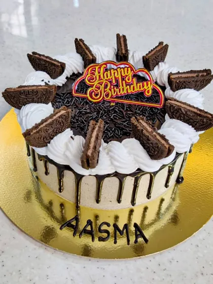 A slice of heaven, ready to eat. This chocolate mousse cake features a chocolate drip and is topped with whipped cream and crushed Oreo-style cookies for extra texture and flavor.