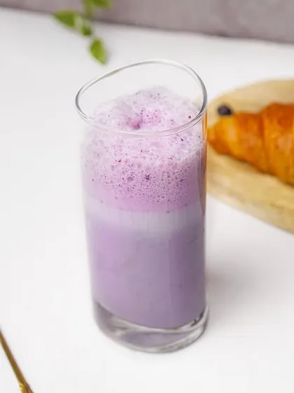 A bright and refreshing blueberry smoothie served in a tall glass, paired with a flaky croissant in a clean, lifestyle setting. This image demonstrates my ability to create appealing breakfast and cafe scenes for websites and social media.