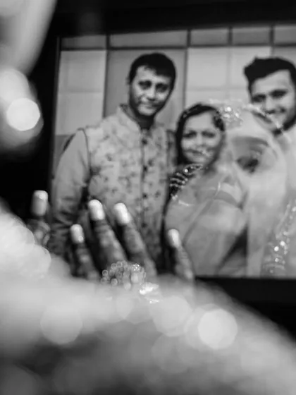 A creative and emotional shot, where a person looks at an old family photo on a screen, connecting the past with the present on a momentous day.