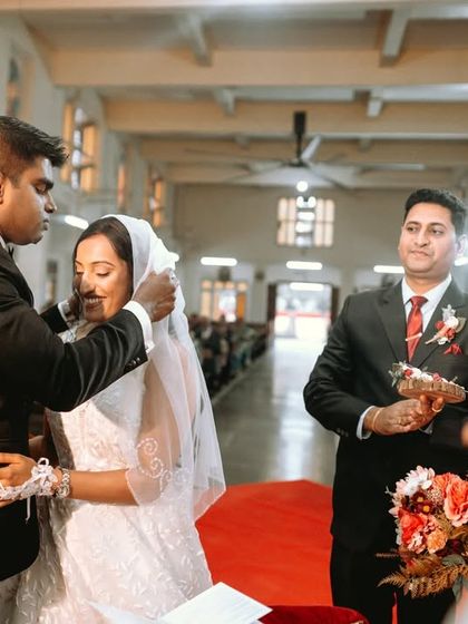 The groom lifts the bride's veil, a significant and emotional moment in a Catholic wedding ceremony.