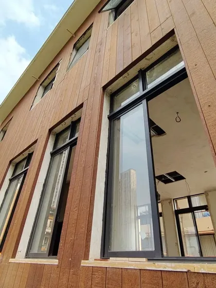 A building facade clad in Weathertex panels, a durable and sustainable wood composite. The installation is shown here with our high-performance system windows, demonstrating our integrated approach.