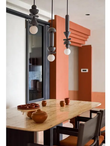The custom suspended wooden light fixtures hang like sculptures above the dining table, contrasting elegantly against the white wall.