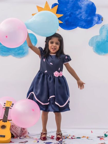 Ready for fun in a navy blue dress with pink floral details. The design is both elegant and playful, perfect for a party atmosphere filled with balloons and confetti.