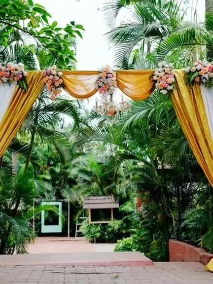 A daytime entrance arch decorated with yellow and white drapes and florals, offering a bright and cheerful welcome to wedding guests.