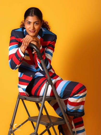 A relaxed and confident pose on a ladder, adding an unconventional element to the shoot. Her expression is calm and engaging.