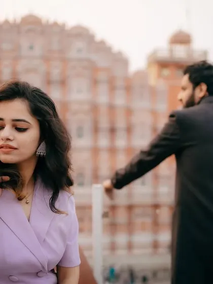 A beautifully composed pre-wedding shot in Jaipur, with the Hawa Mahal in the background. The photo plays with focus and perspective to create a sense of story and anticipation.