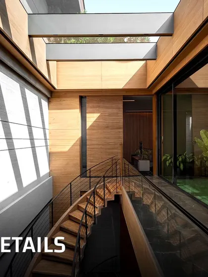Details are everything. This image shows a wooden staircase with a glass railing, set against a board-formed concrete wall. The skylight above casts shifting patterns of light and shadow, bringing the static architecture to life throughout the day.